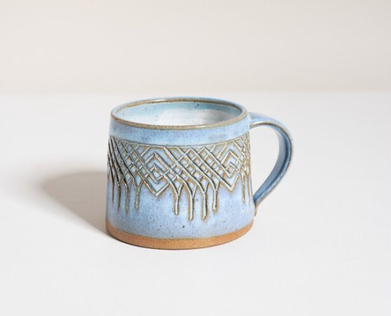 A light blue mug with handcarved lines into it. 